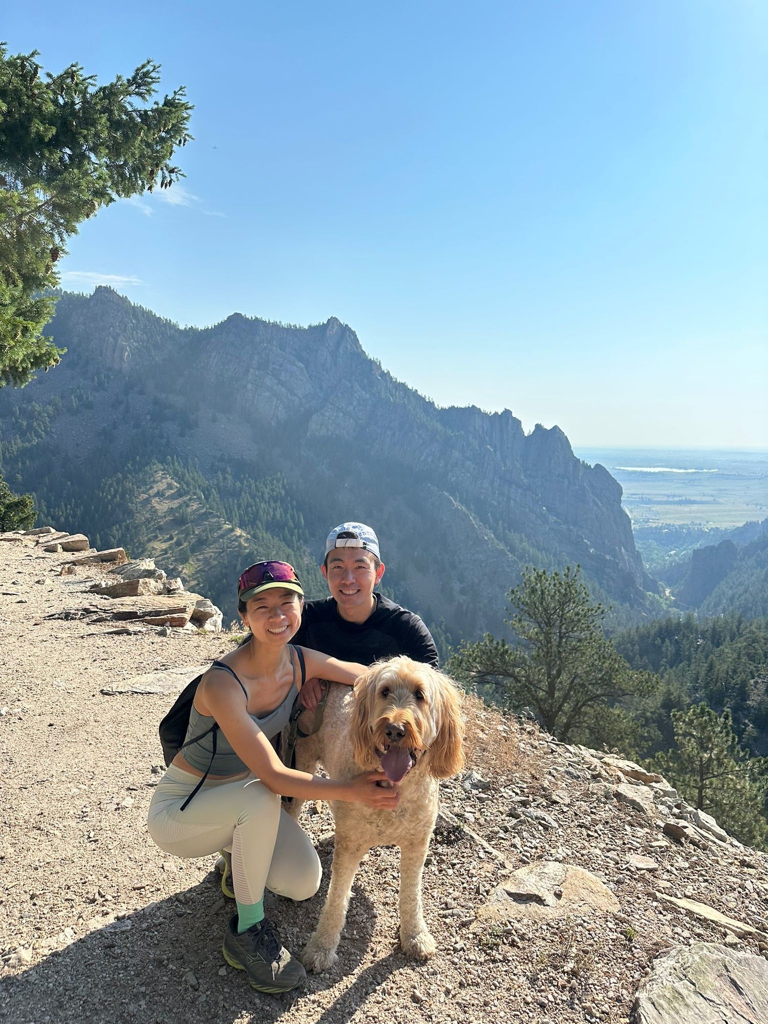 Founders with Goldendoodle Archie on a mountain trail with scenic views.